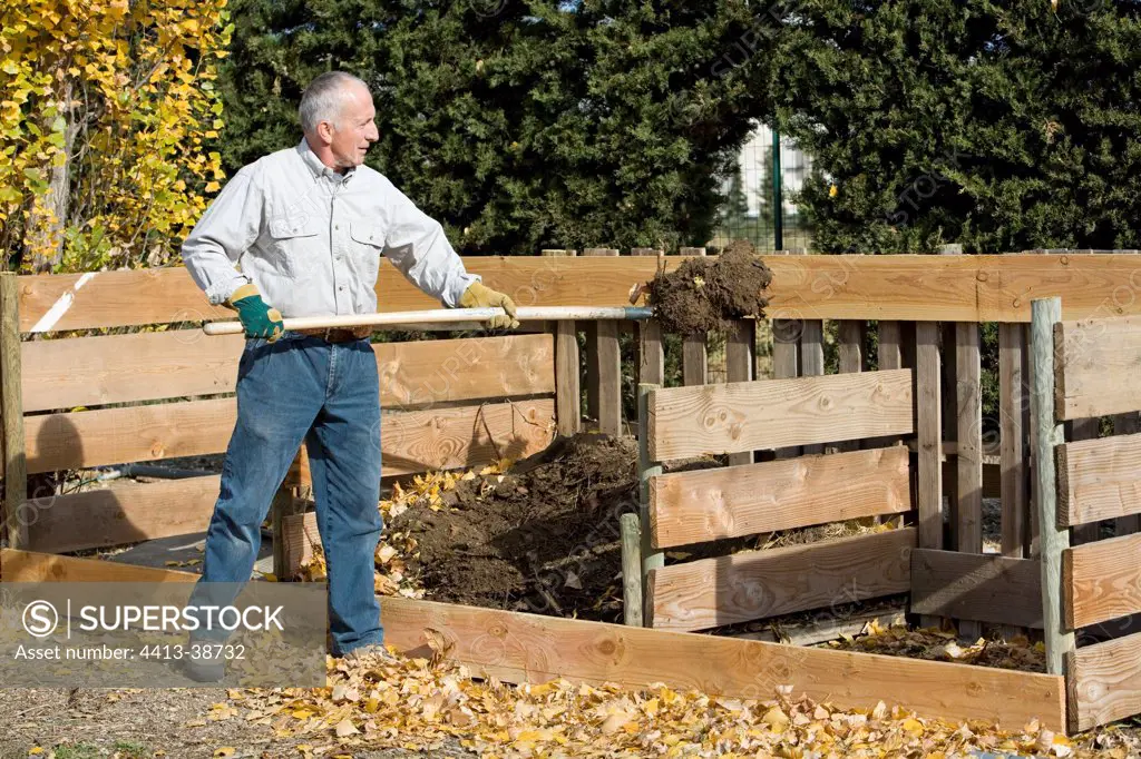Man turning around the compost in a garden in autumn