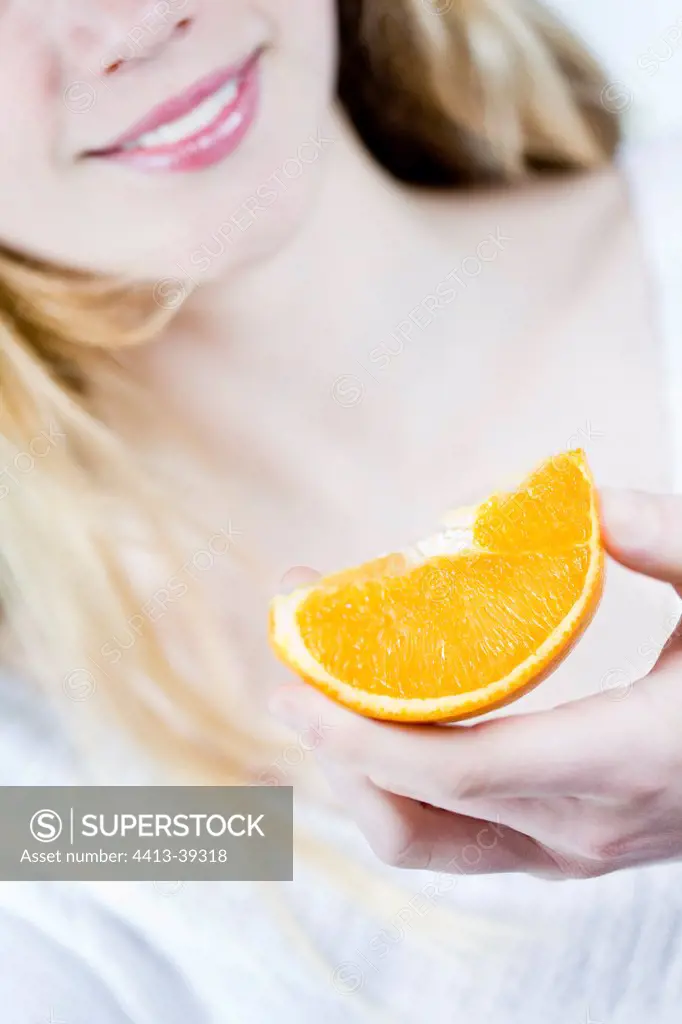 Young woman eating an orange quarter
