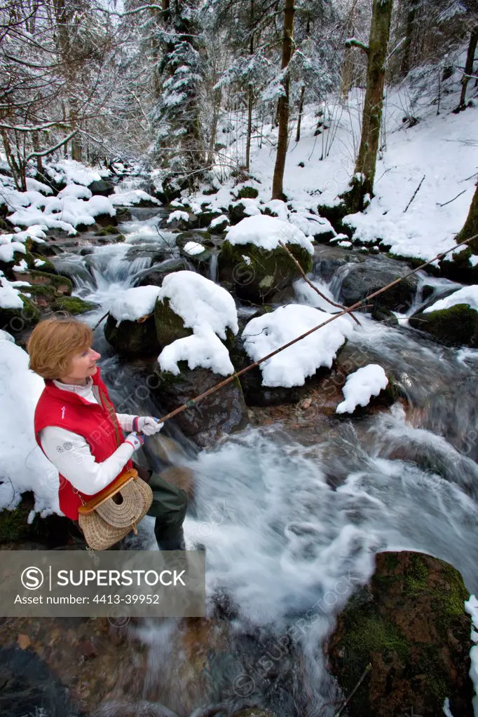 Woman fishing in a mountain river in winter Sewen