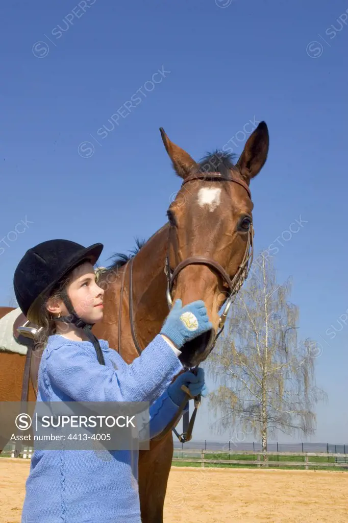 Young rider on the ground stroking her Horse's nostrils