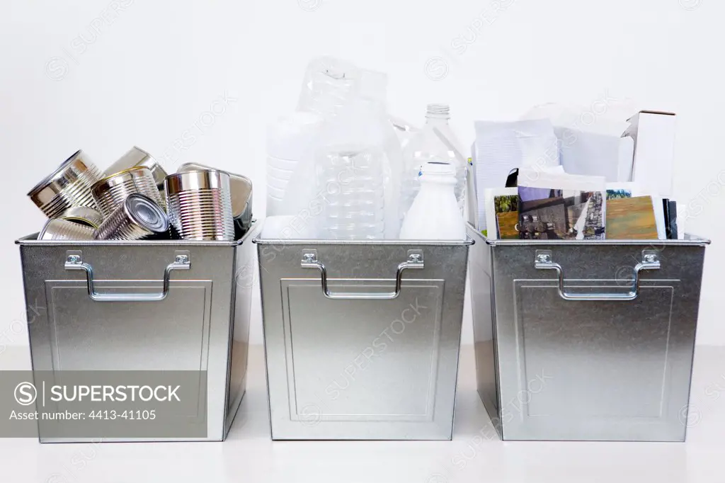Three steel bins containing recyclable items