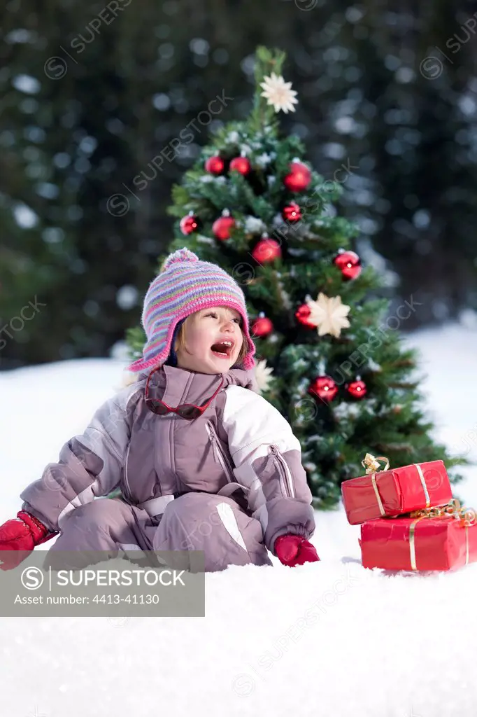 Girl with gifts in front of a Christmas Tree in snow Alps