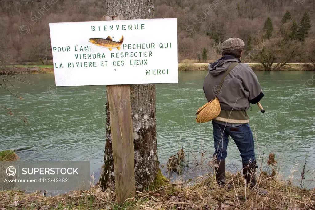 Fisherman near an information panel on the Loue river