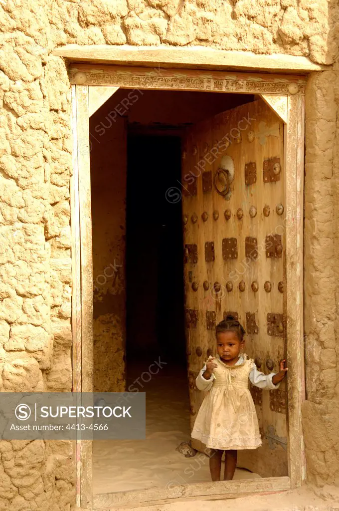 Young girl in front of a house with tombouctian door Mali