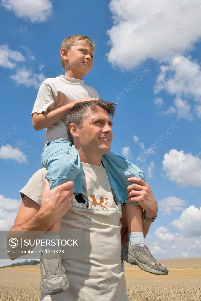 Farmer holding son on his shoulders in a ripe Wheat field