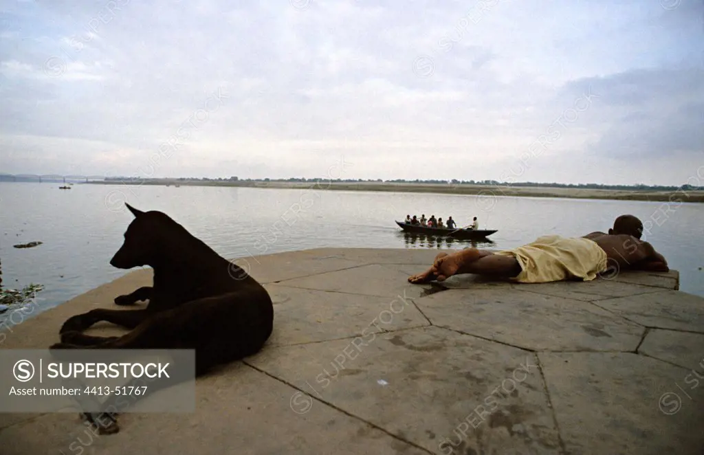 Dog and man lying beside the Ganges Vrnaçî India