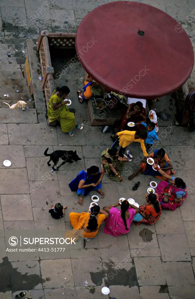 Women eating in the street and dog Vrnaçî India