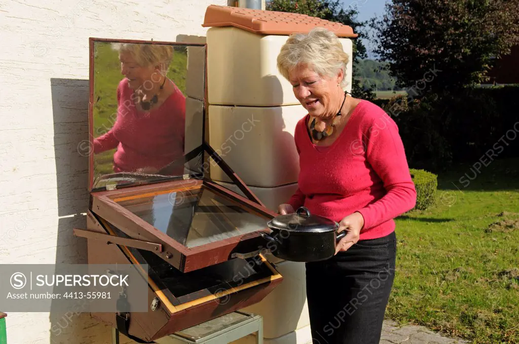 Woman using a solar oven in front of a house Belfort France