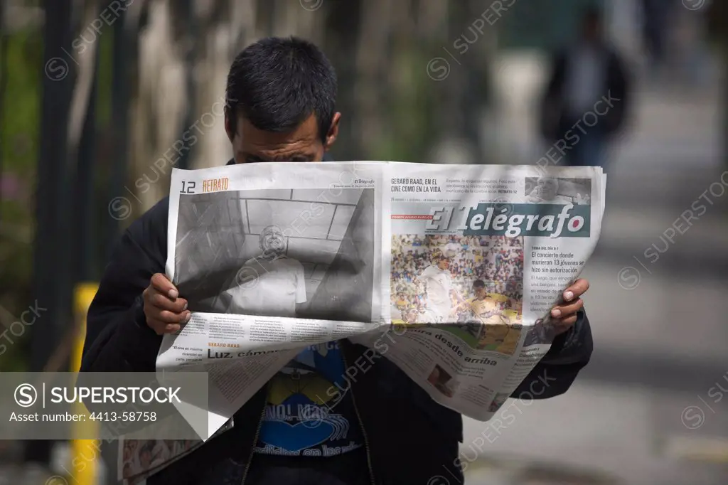 Man standing reading the paper in the street Quito Ecuador