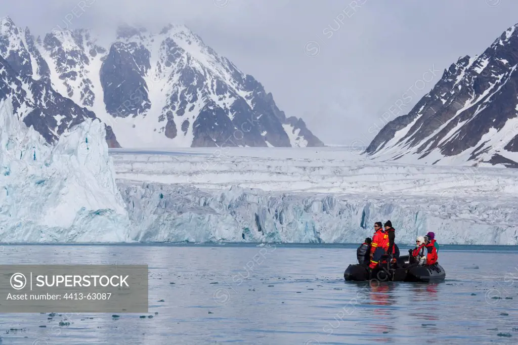 Tourists cruising in front of large glacier in of fiord