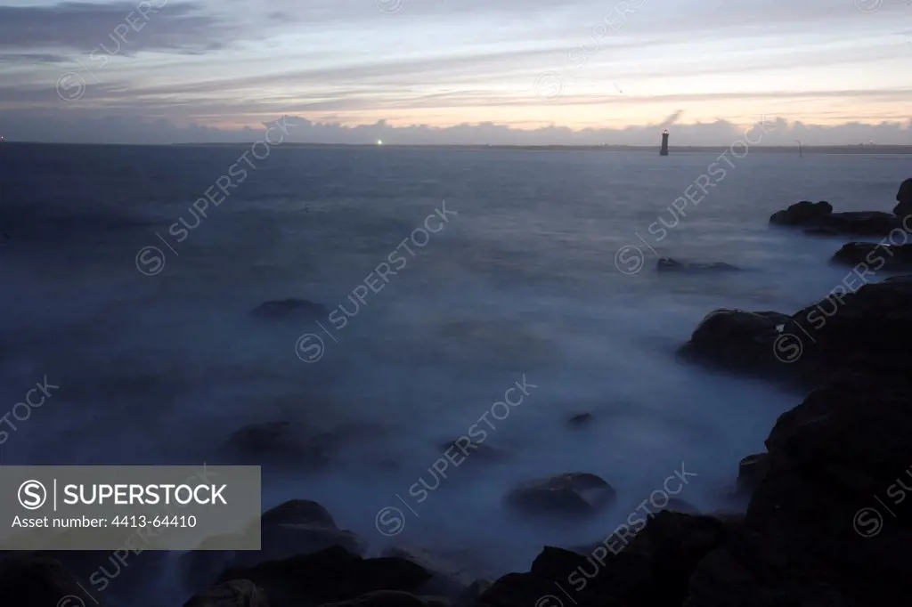 Foam on the rocky shore of the Ile de Bannec at twilight