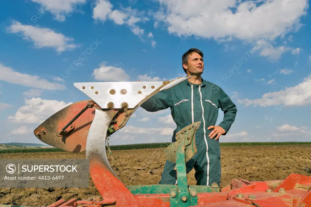 Portrait of farmer pressed on his plough in a field