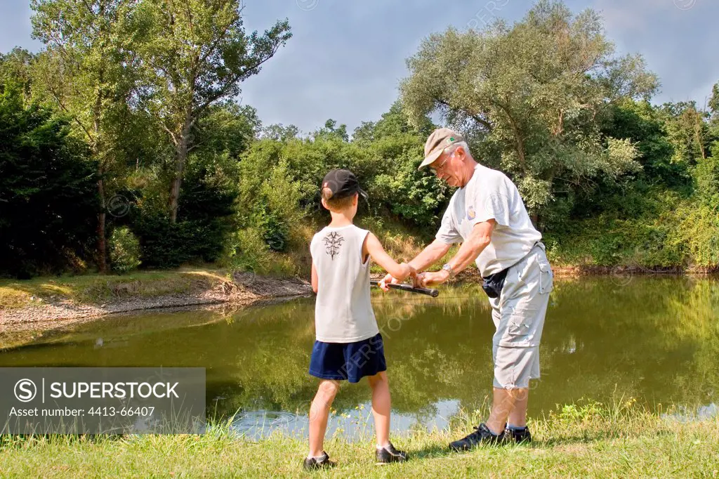 Child and monitors fishing on the edge of a pond Pfastatt