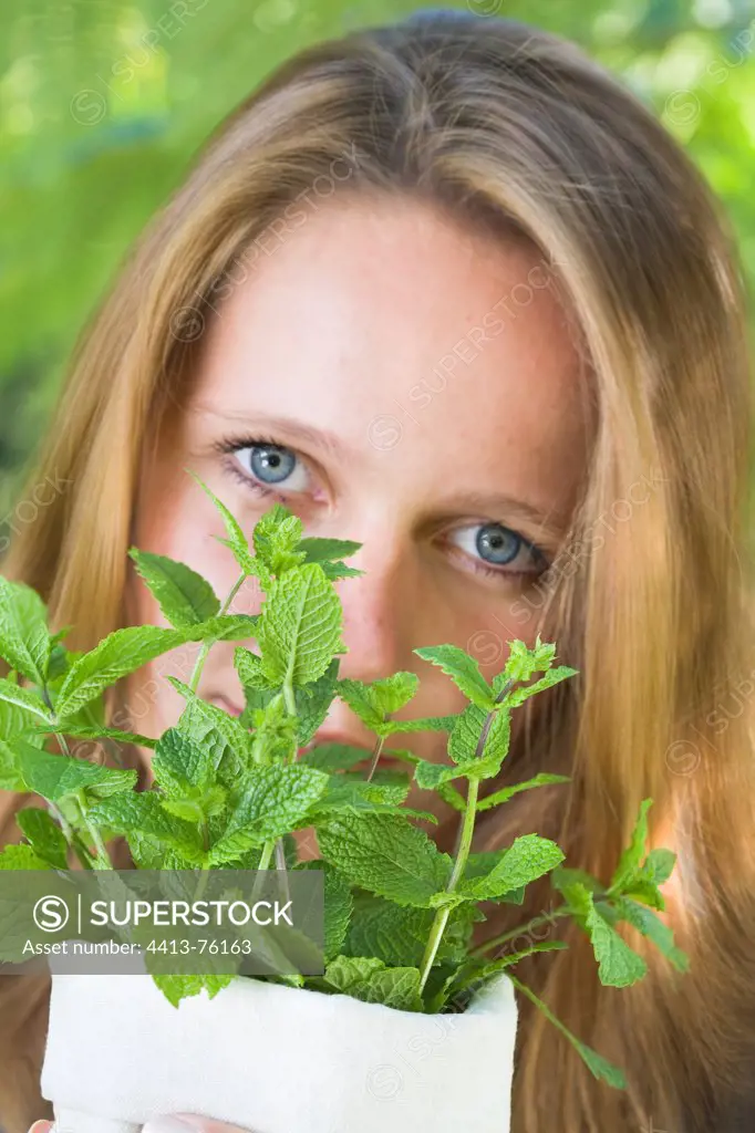 Young woman smelling a bouquet of fresh mint in garden