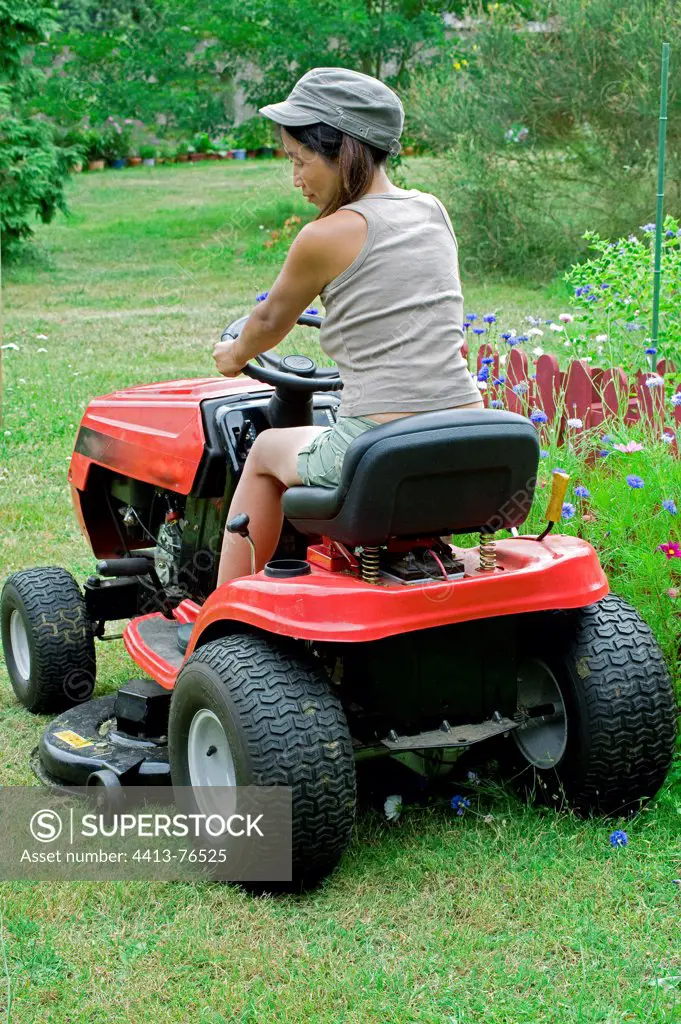 Woman mowing the lawn on a lawn mower