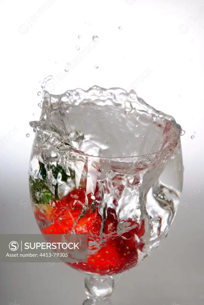 A Strawberry falling in a glass of water
