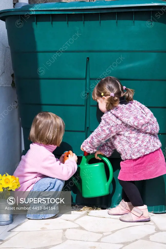 Two small 3 and 4-year-old girls fill a sprinkling can