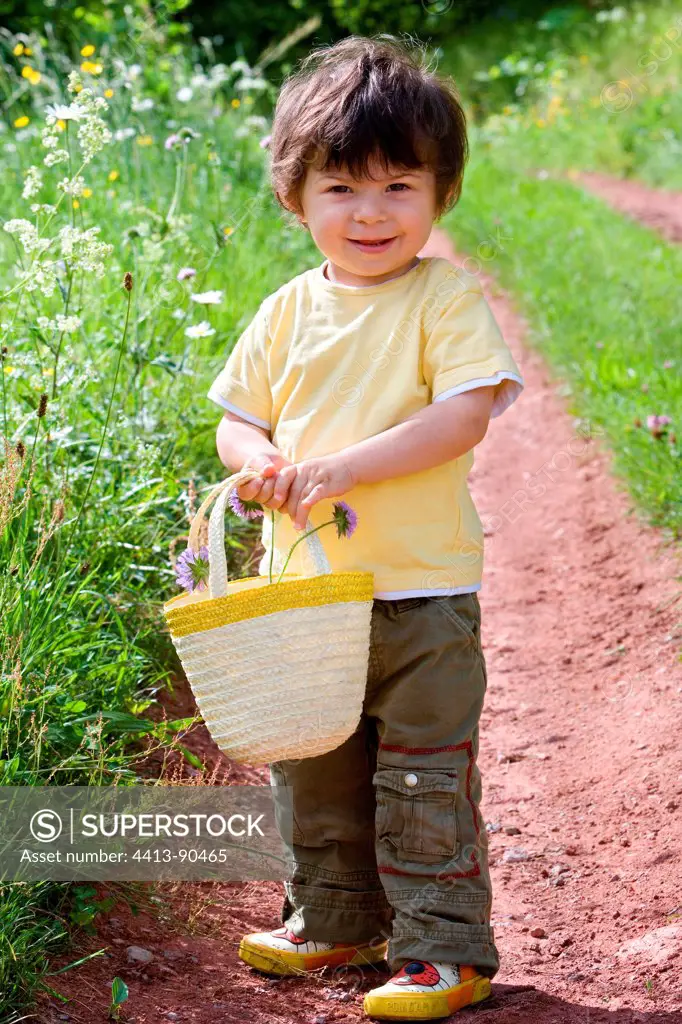 Boy carrying a basket in a flowery meadow Franche-Comte