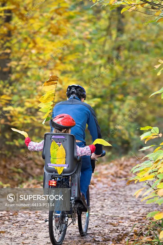 Girl in the back of a bicycle in a forest pathFrance