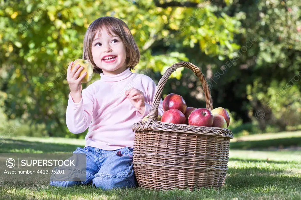 Girl eating an apple on the grass next to a basketFrance