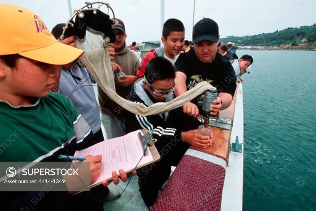 USA, California, Children examining tools and techniques of marine science onboard research vessel
