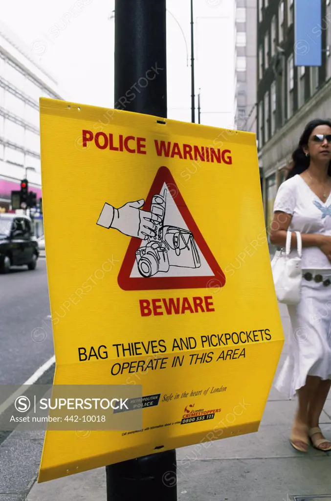 Close-up of a police warning sign on the sidewalk of a street, London, England