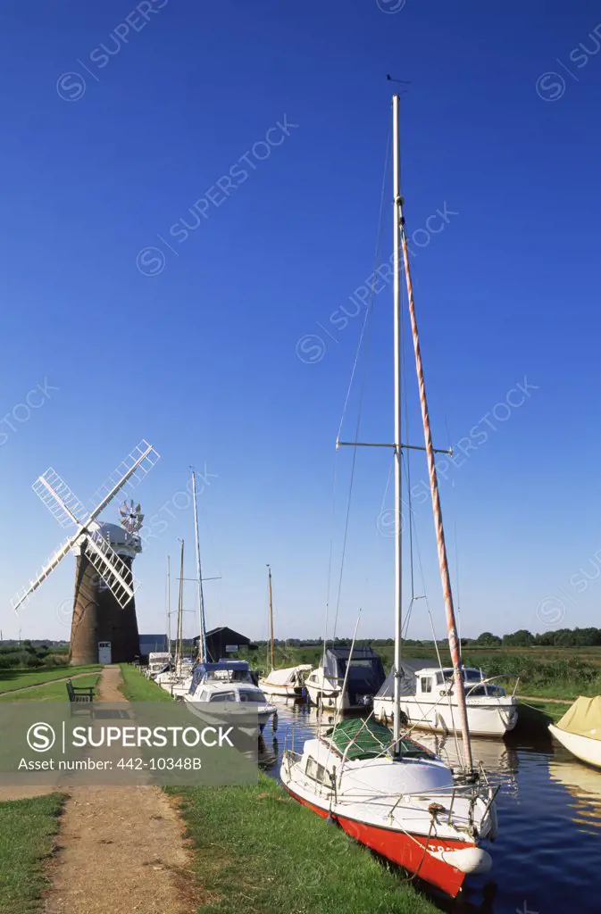 Boats moored near a traditional windmill, Horsey Windpump, Horsey, Norfolk Broads, Norfolk, England