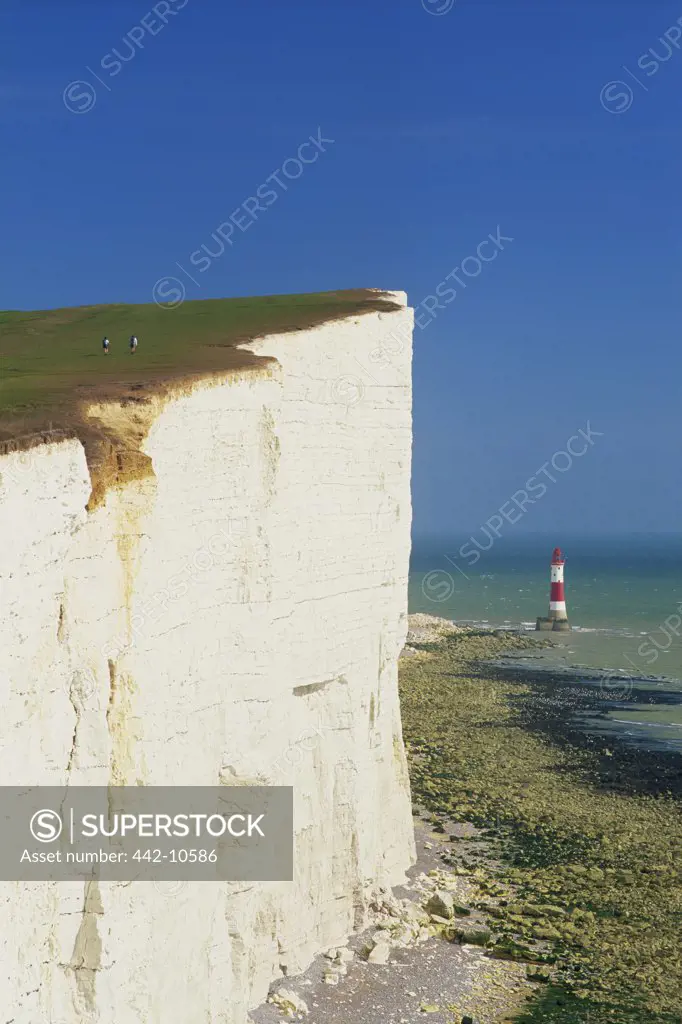 Limestone cliff with a lighthouse in the background, Beachy Head, Eastbourne, East Sussex, England