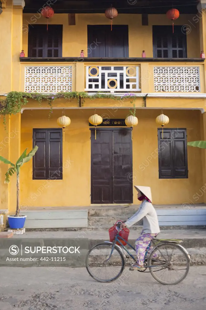 Person riding a bicycle in front of a cafe, Hoi An, Vietnam