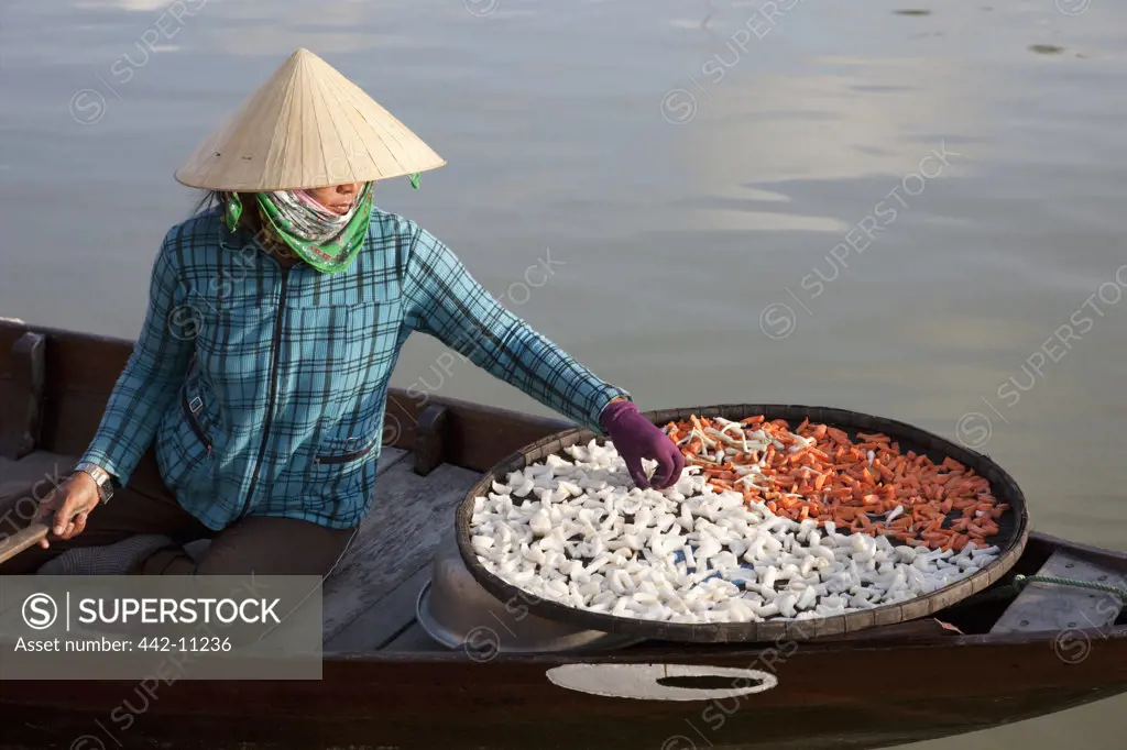 Female vendor selling dried food in a boat, Hoi An, Vietnam