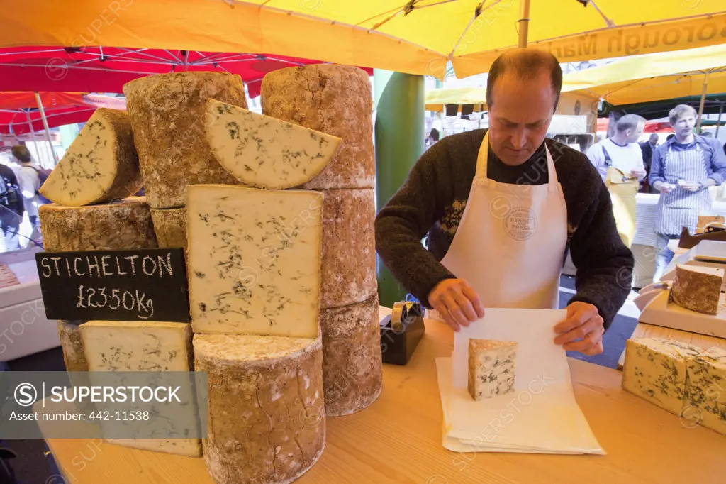 UK, England, London, Southwark, Borough Market, market vendor wrapping cheese
