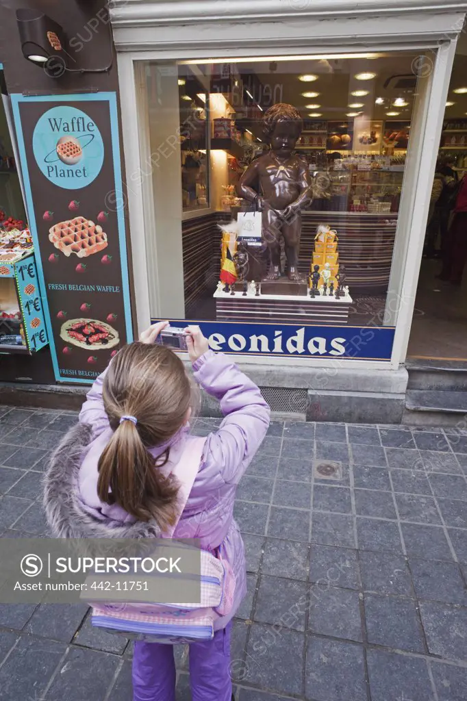 Belgium, Brussels, Young girl taking picture of Mannekin Pis Statue in chocolate shop