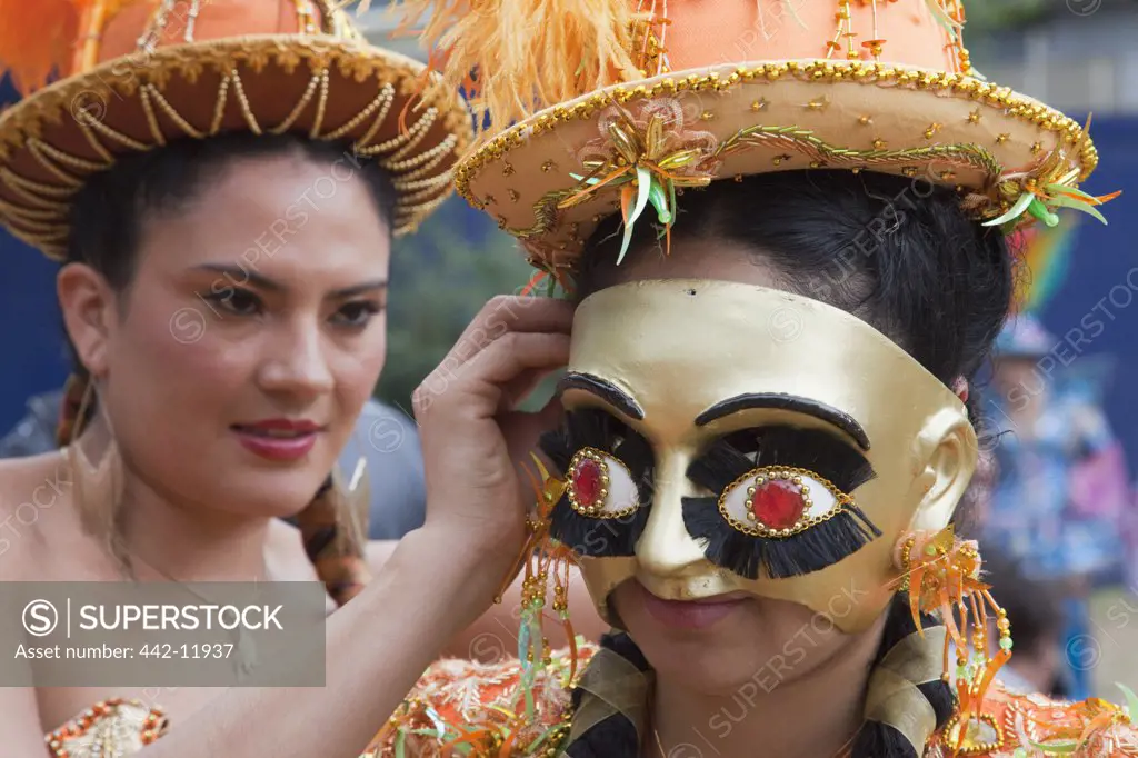 UK, England, London, Young woman preparing masked Bolivian participant for Carnival Del Pueblo, Carnaval Del Pueblo Festival is Europes Largest Latin Street Festival