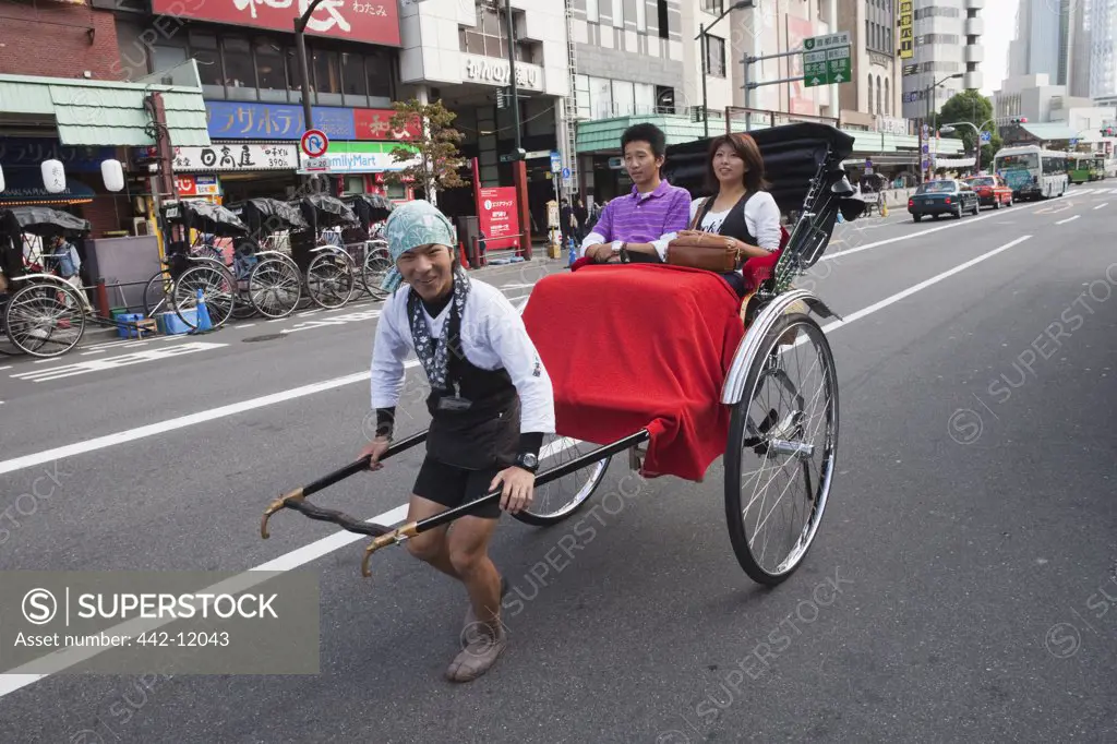Man pulling passengers in a rickshaw, Asakusa, Tokyo Prefecture, Japan