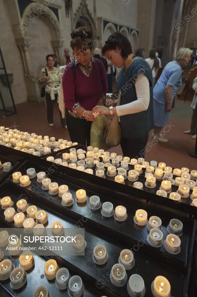 Worshippers lighting votive candles in a cathedral, Cathedral Of Saint Peter, Trier, Germany
