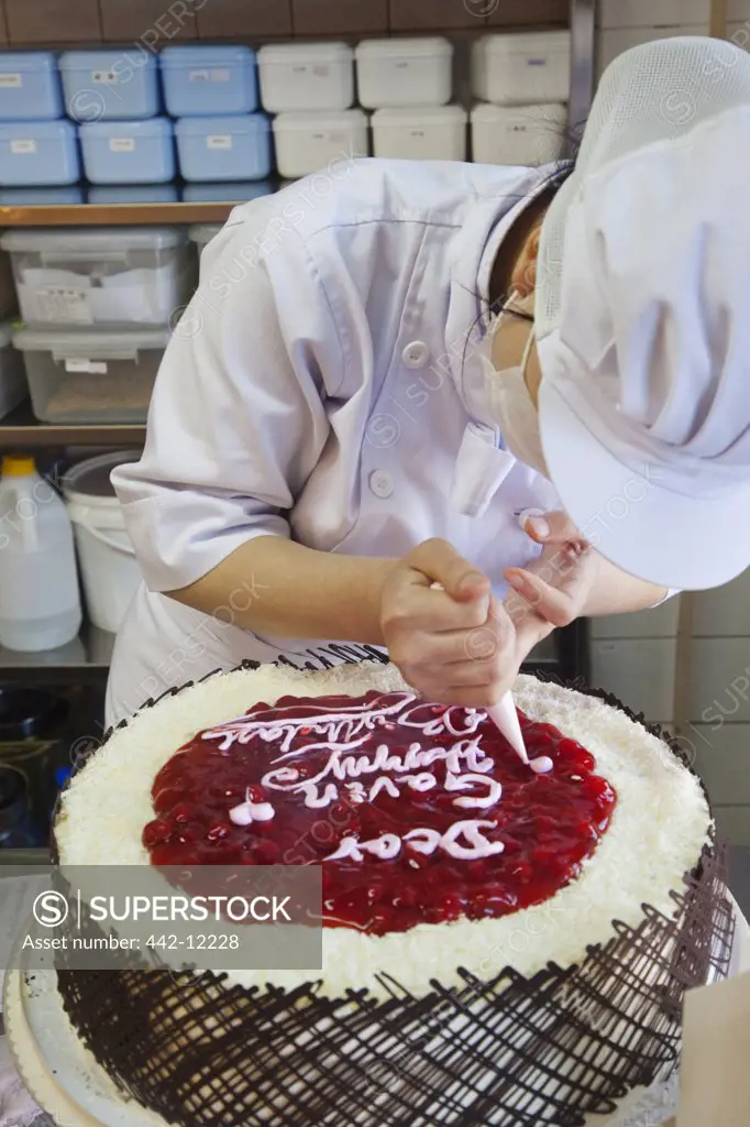 Female chef decorating a birthday cake, Beijing, China