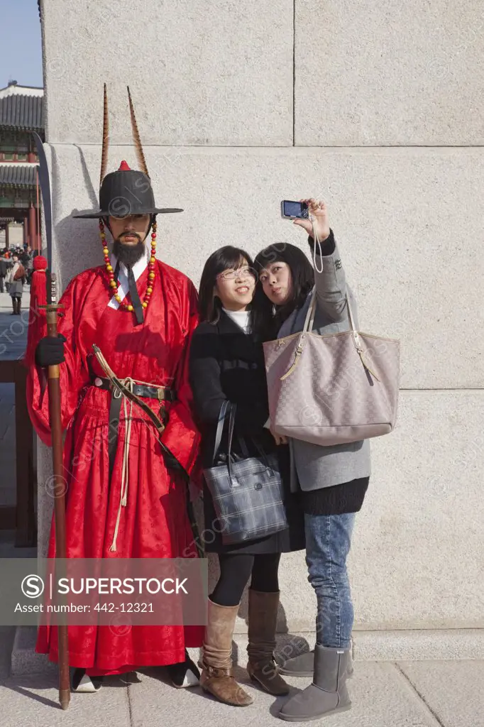 Teenage girls posing with ceremonial guard in traditional uniform, Gyeongbokgung Palace, Seoul, South Korea