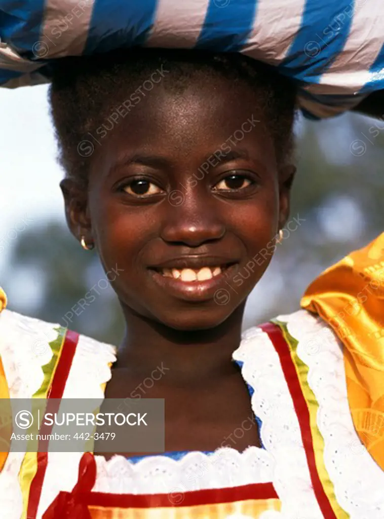Portrait of a girl smiling and carrying a bundle on her head, Banjul, Gambia
