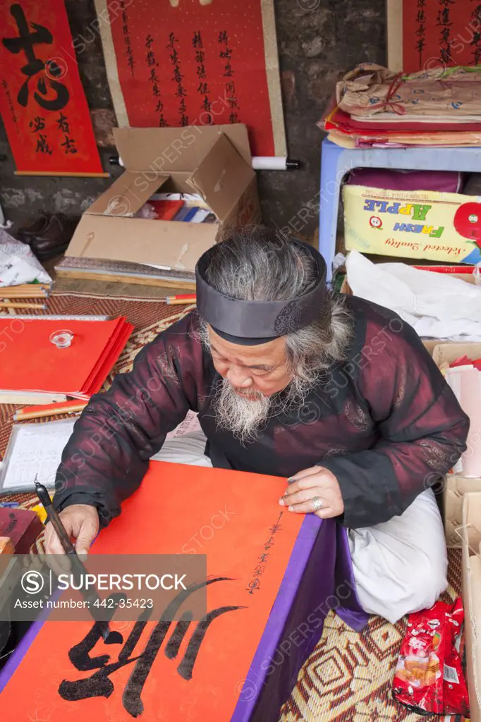 Senior man painting calligraphy on a paper in a temple, Temple Of Literature, Hanoi, Vietnam