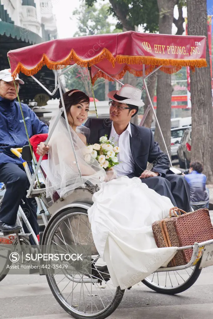 Newlywed couple sitting in a rickshaw, Hanoi, Vietnam