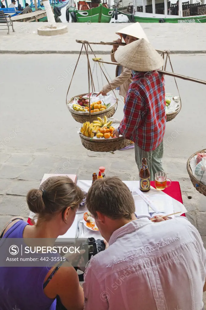 Women selling fruits in front of a cafe, Hoi An, Vietnam