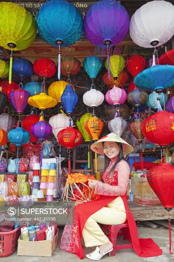 Teenage girl making paper lanterns at a market stall, Hoi An, Vietnam