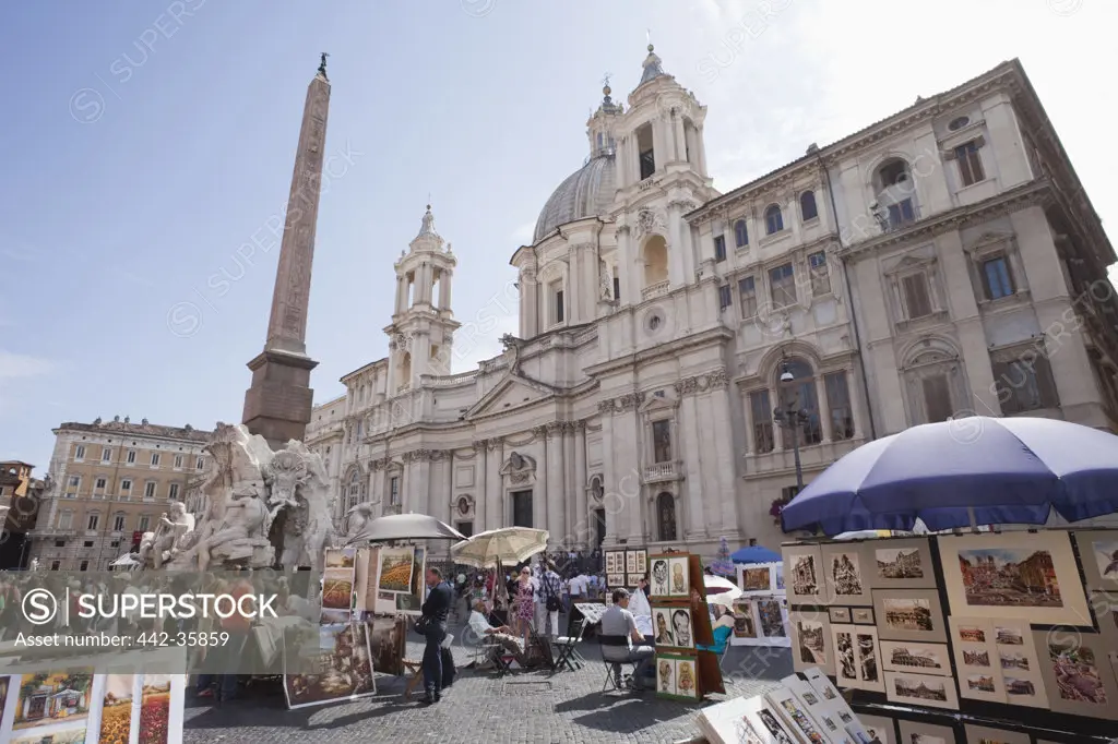 Italy, Rome, Souvenir stalls at Piazza Navona with Sant'Agnese in Agone and Fountain of the Four Rivers in background