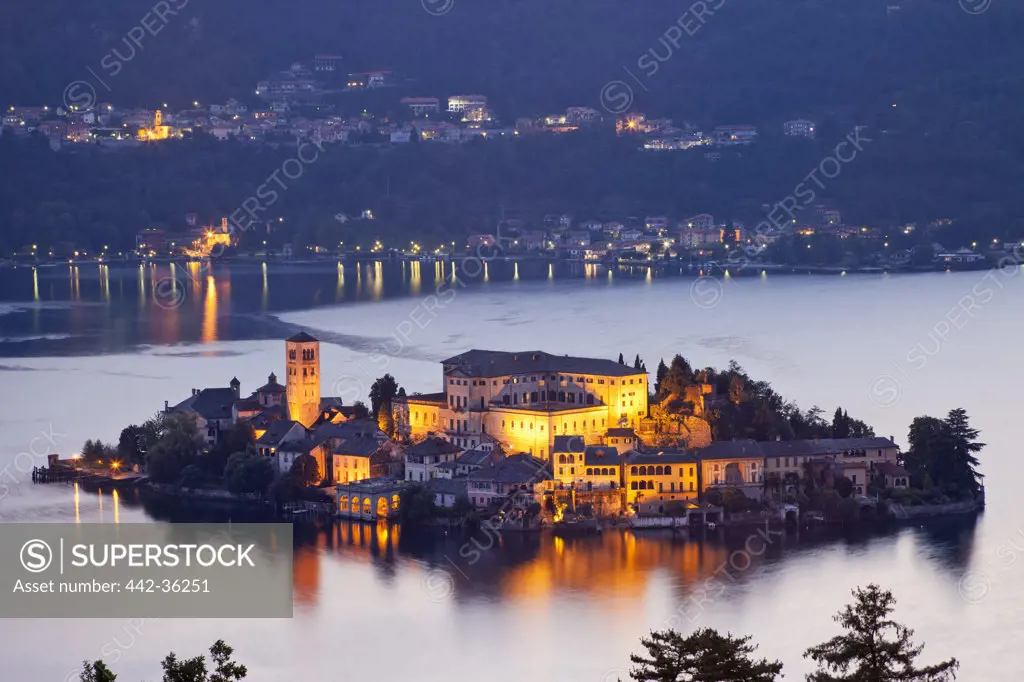 High angle view of a town on an island lit up at dusk, San Giulio Island, Lake Orta, Piedmont, Italy