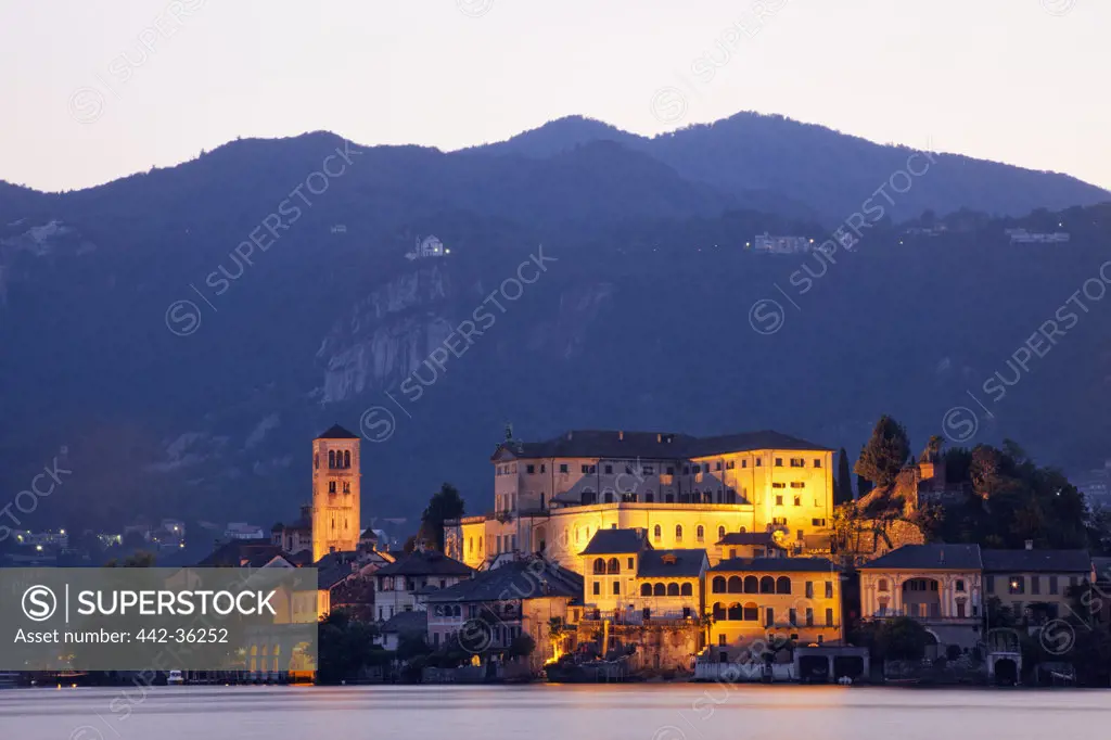 Town on an island lit up at dusk, San Giulio Island, Lake Orta, Piedmont, Italy