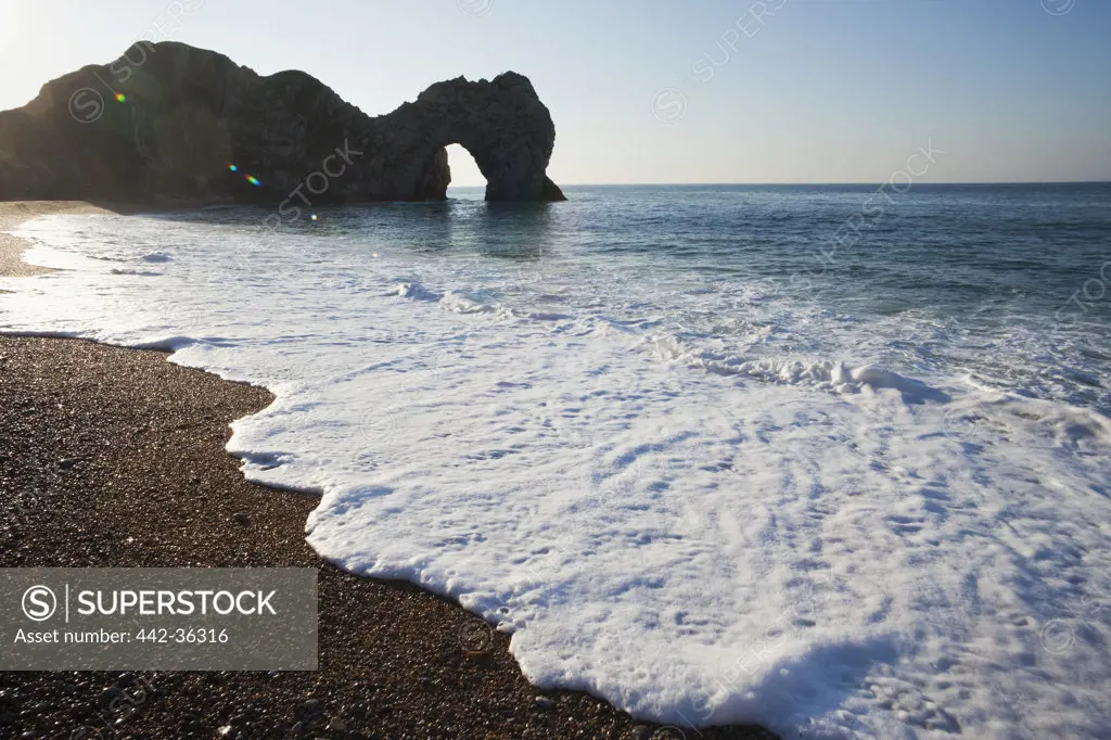 Surf with natural limestone arch on the beach, Durdle Door Beach, Jurassic Coast, Dorset, England