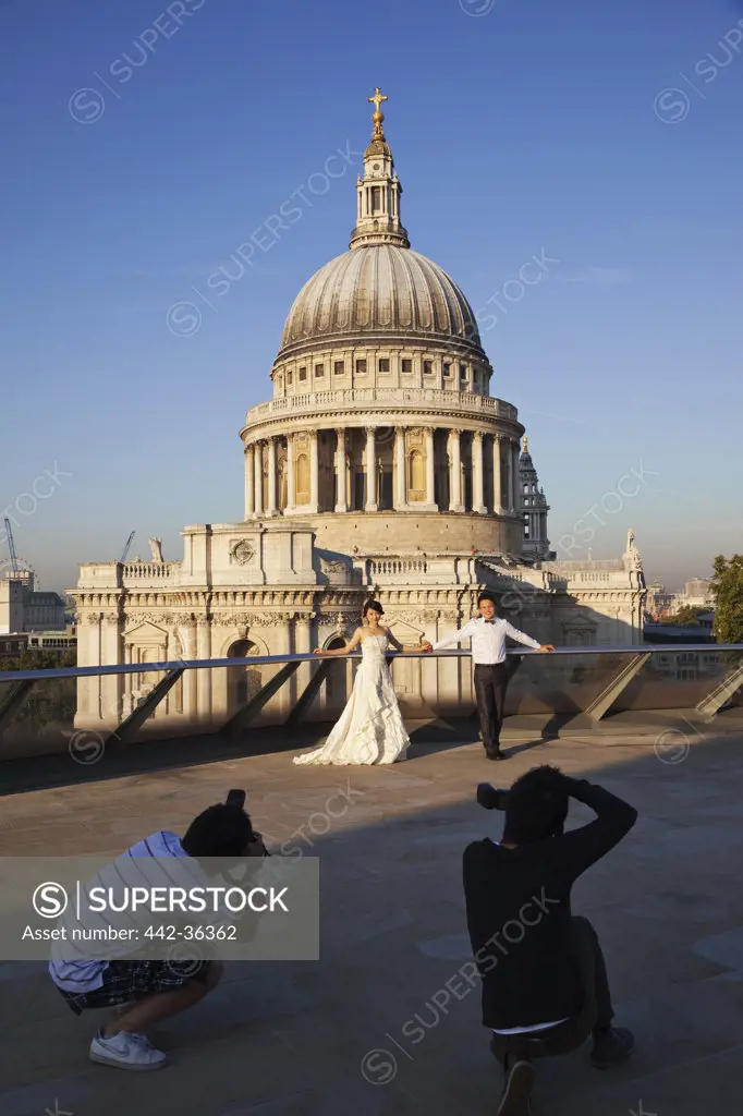 Newlywed couple posing for photographers in front of the cathedral, St. Paul's Cathedral, City of London, London, England