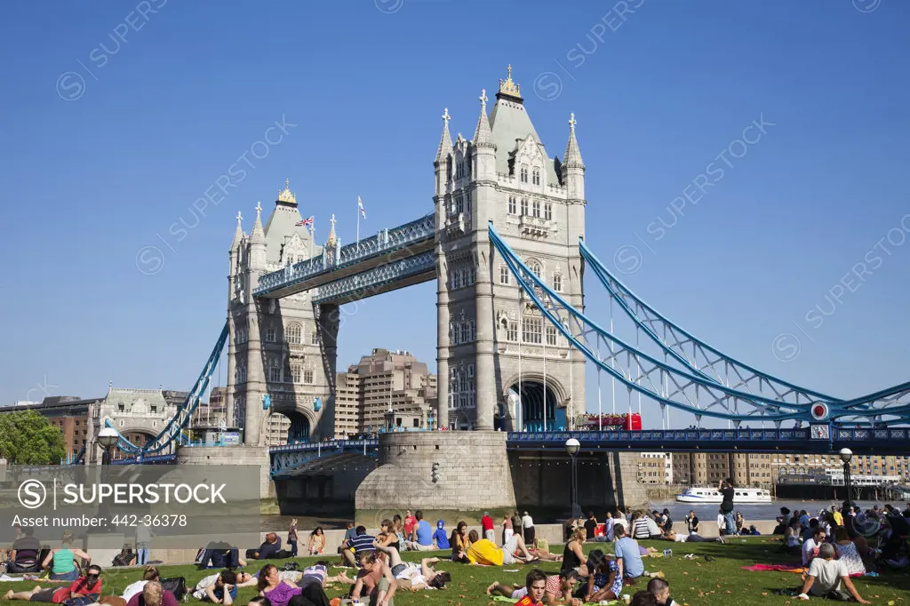 Tourists sitting near a bridge, Tower Bridge, Thames River, London, England