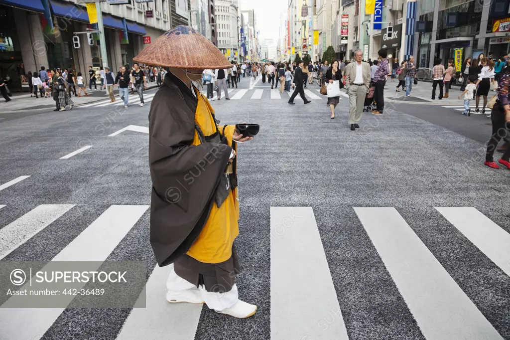 Monk crossing a road while collecting alms in a street, Ginza, Tokyo, Japan