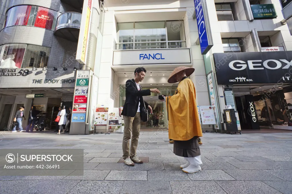 Monk receiving alms from a man, Ginza, Tokyo, Japan